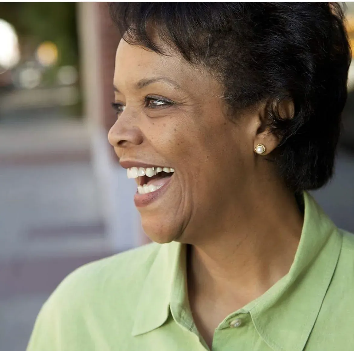 An actor in a green shirt laughs off camera
